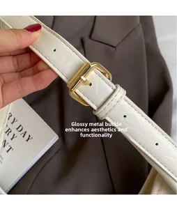 Detail of adjustable white leather strap with polished gold buckle on tote bag