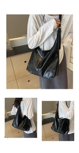 Close-up of vintage black pleated tote bag with golden buckle and wide shoulder strap