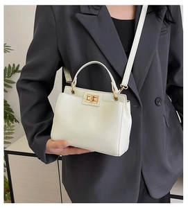 Close-up of white leather handbag with golden twist lock on model in black blazer