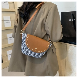 Detail of crossbody bag with houndstooth fabric, brown leather flap and gold metal studs