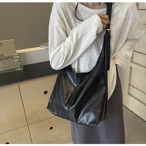 Detailed view of black pleated tote bag showing wrinkled leather texture and gold buckle