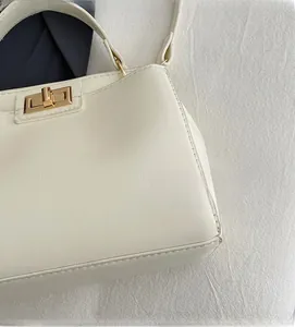 Detailed close-up of ivory textured leather handbag with gold rectangular twist lock
