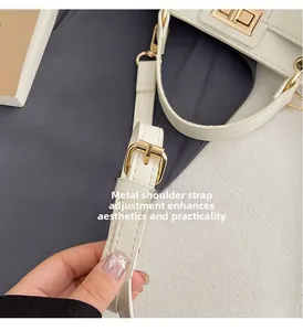 Detail of adjustable pale gold hardware buckle on a white leather shoulder strap