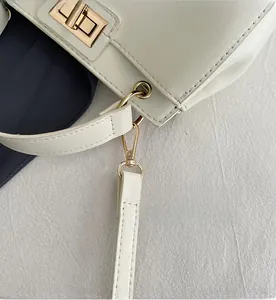 Detail of premium light-gold hardware and white leather texture on stylish handbag