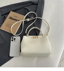 Cream vintage handbag size comparison with a smartphone showing golden twist lock