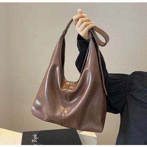 Detail of a large brown tote bag with embossed floral texture and crescent moon design