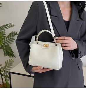 Detail of white vintage leather handbag with gold twist-lock and top handle on model