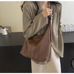 Détail d'un grand sac cabas marron foncé en cuir PU avec texture brillante et boucle dorée