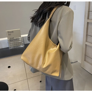 Detail of large mustard yellow hobo tote bag with wrinkled texture worn on shoulder