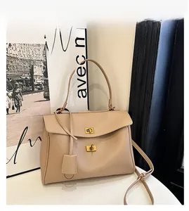 Detail of beige leather handbag with gold metal twist lock and adjustable shoulder strap