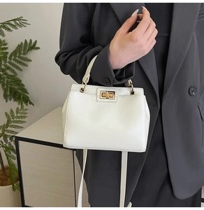 Detail shot of the white leather handbag featuring a gold metal square twist lock closure