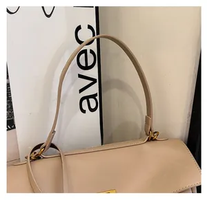 Detail view of the beige leather handbag showing the sturdy handle and gold metal hardware