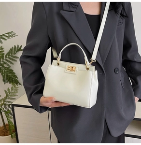 Detail of off-white leather handbag with gold twist lock and adjustable shoulder strap