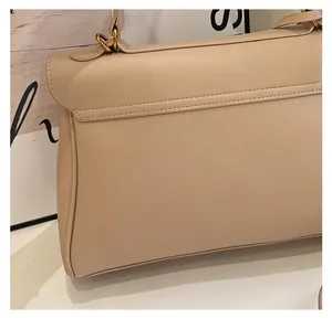 Detailed view of beige leather handbag featuring reinforced stitching and gold metal hardware
