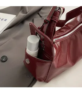 Detail view of burgundy patent leather bag side pocket with magnetic closure