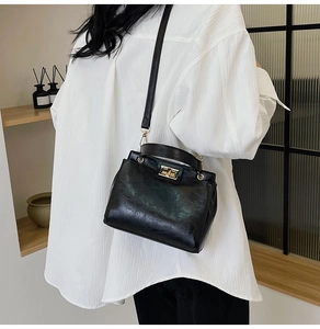 Detail of vintage black leather handbag featuring iconic gold twist lock and metal hardware