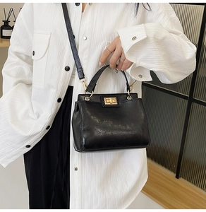 Detail of black crossbody bag with gold twist lock and adjustable leather shoulder strap