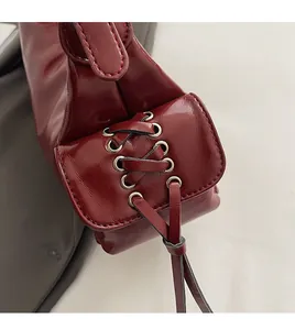 Detail of dark red PU shoulder bag featuring side lace-up design and smooth hand-stitching