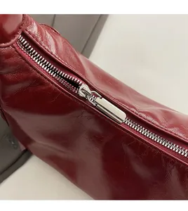 Close-up of durable silver metal zipper on vintage red soft leather shoulder bag