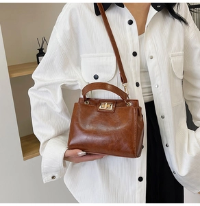 Brown vintage leather handbag detail with metallic twist-lock closure and adjustable strap