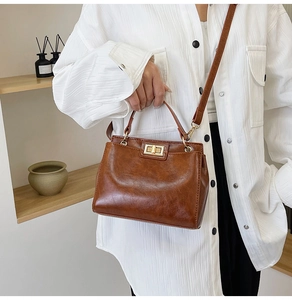 Detail of vintage brown leather handbag with golden twist lock and top handle strap