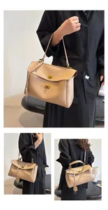 Detail of beige soft leather tote bag showing metal twist lock and adjustable shoulder strap