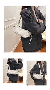 Detail view of a white glossy leather underarm bag with side drawstring accents