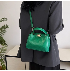 Detail of emerald green vintage crossbody bag with a glossy texture and metal turn-lock