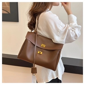 Detailed side view of the brown leather shoulder bag featuring a gold metal buckle