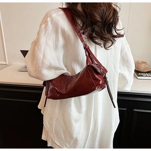 Deep red glossy leather underarm bag with side tassel detail in a lifestyle back view