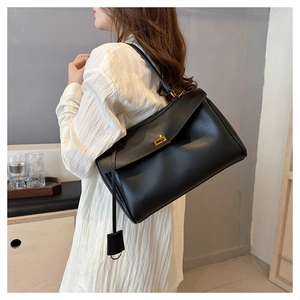 Detailed view of black leather tote bag featuring elegant golden square twist-lock closure