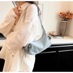 Close-up of light blue denim fabric shoulder bag with side tassel drawstring details