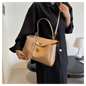 Detail of minimalist beige leather tote with gold twist lock and top handle