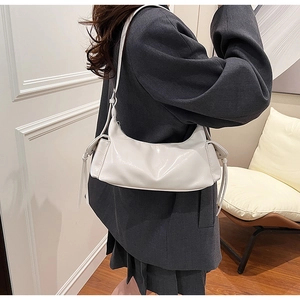 Detailed view of white semi-circle underarm bag featuring drawstring and glossy finish