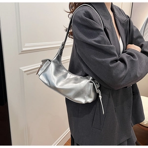 Detail of metallic silver hobo bag with side tassel on a model in a grey blazer
