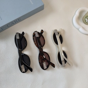 Detailed view of oval cat-eye sunglasses with silver metal chain link temple accents