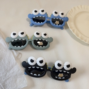 Kids monster sunglasses with large eyes and teeth design in blue, green, and black