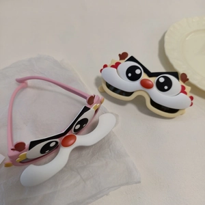 Close-up of pink and beige kids cartoon dinosaur sunglasses with flip-up 3D design