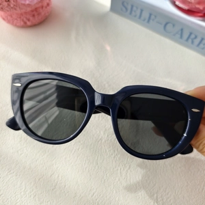 Dettaglio occhiali da sole cat-eye blu navy con frecce argentate e montatura lucida