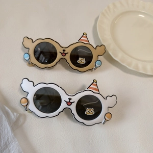Flat lay of bear-themed children's sunglasses with cartoon balloon and party hat accents