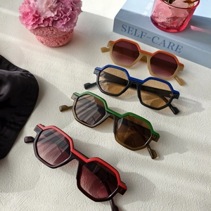 Close-up of geometric octagonal sunglasses in four color combinations on a textured desk
