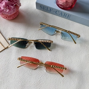 Detail of rimless sunglasses featuring golden pyramid rivets and gradient color lenses