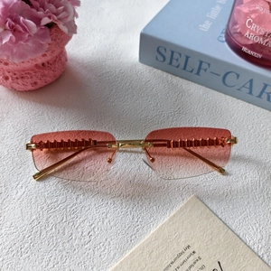 Detail of pink gradient rimless sunglasses with gold metal temples and sawtooth accents