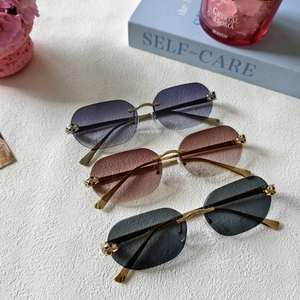 Close-up of rimless gradient sunglasses featuring gold metal leopard head temple details