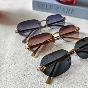 Detail of rimless sunglasses featuring golden cheetah head carving and gradient lenses