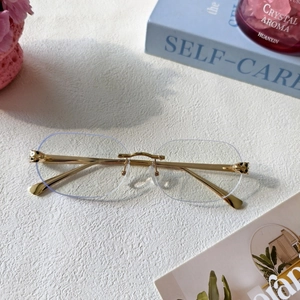 Close-up of golden leopard head hinge on rimless sunglasses with cut-edge lenses