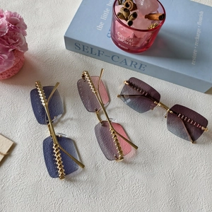 Close-up of rimless rectangle sunglasses with metal rivets and gradient resin lenses