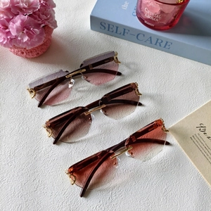 Detailed view of three rimless gradient sunglasses with geometric cut lenses and gold hinges