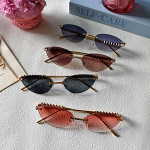 Lunettes de soleil œil-de-chat sans monture rétro avec monture dorée et détails de rivets