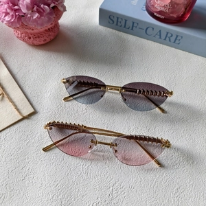 Détail de lunettes de soleil œil-de-chat sans monture avec branches en métal doré chic